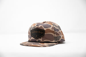 A camouflaged nylon snapback hat with a leather patch on the front.
