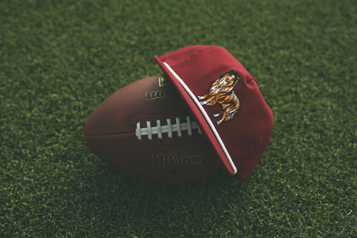 Red cap with tiger logo on a football on grass