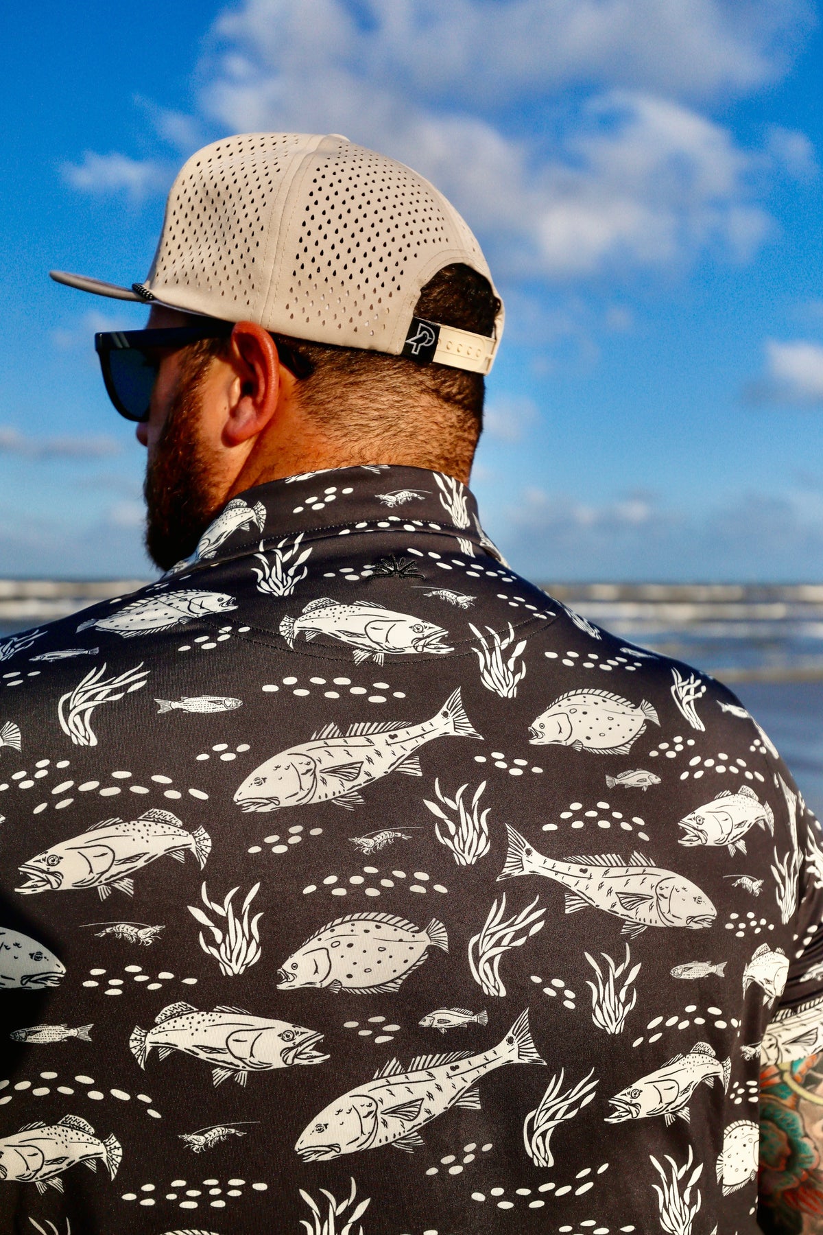 Close-up back view of man wearing black Texas Slam polo and hat.