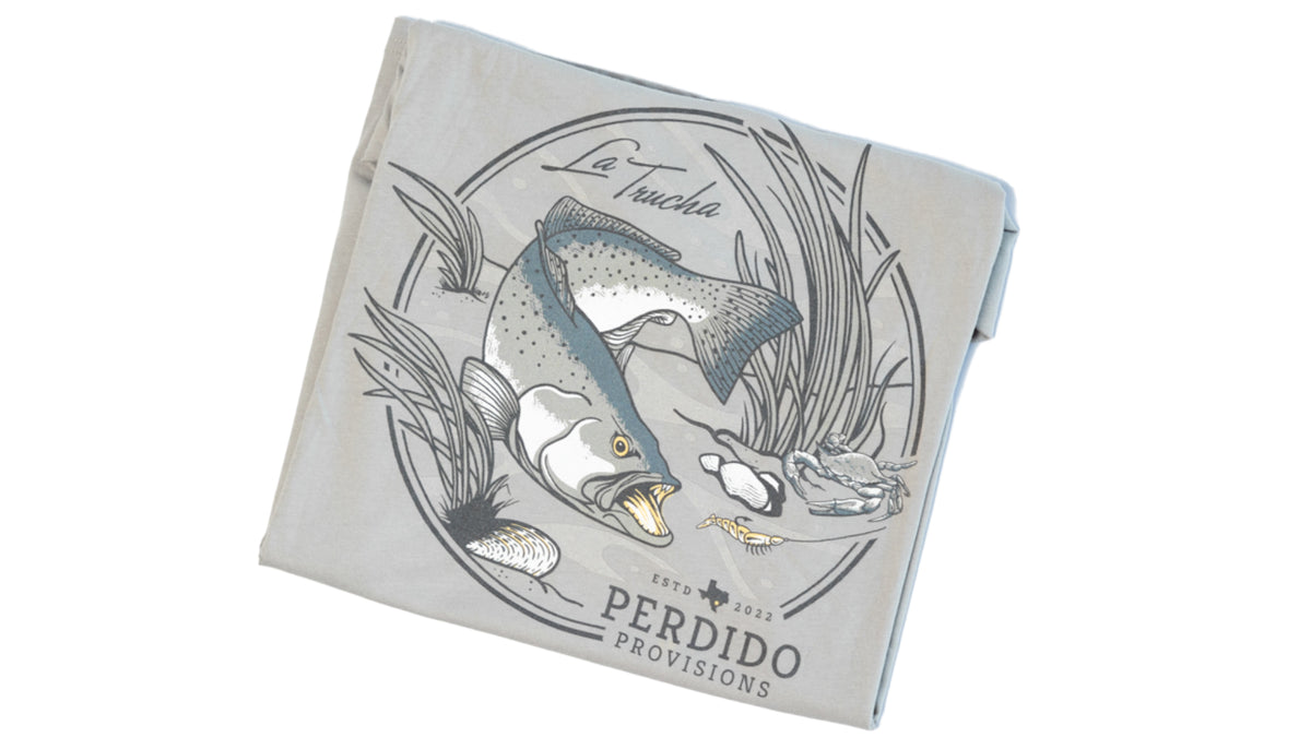 Folded view of La Trucha pocket tee featuring the circular speckled trout back graphic.