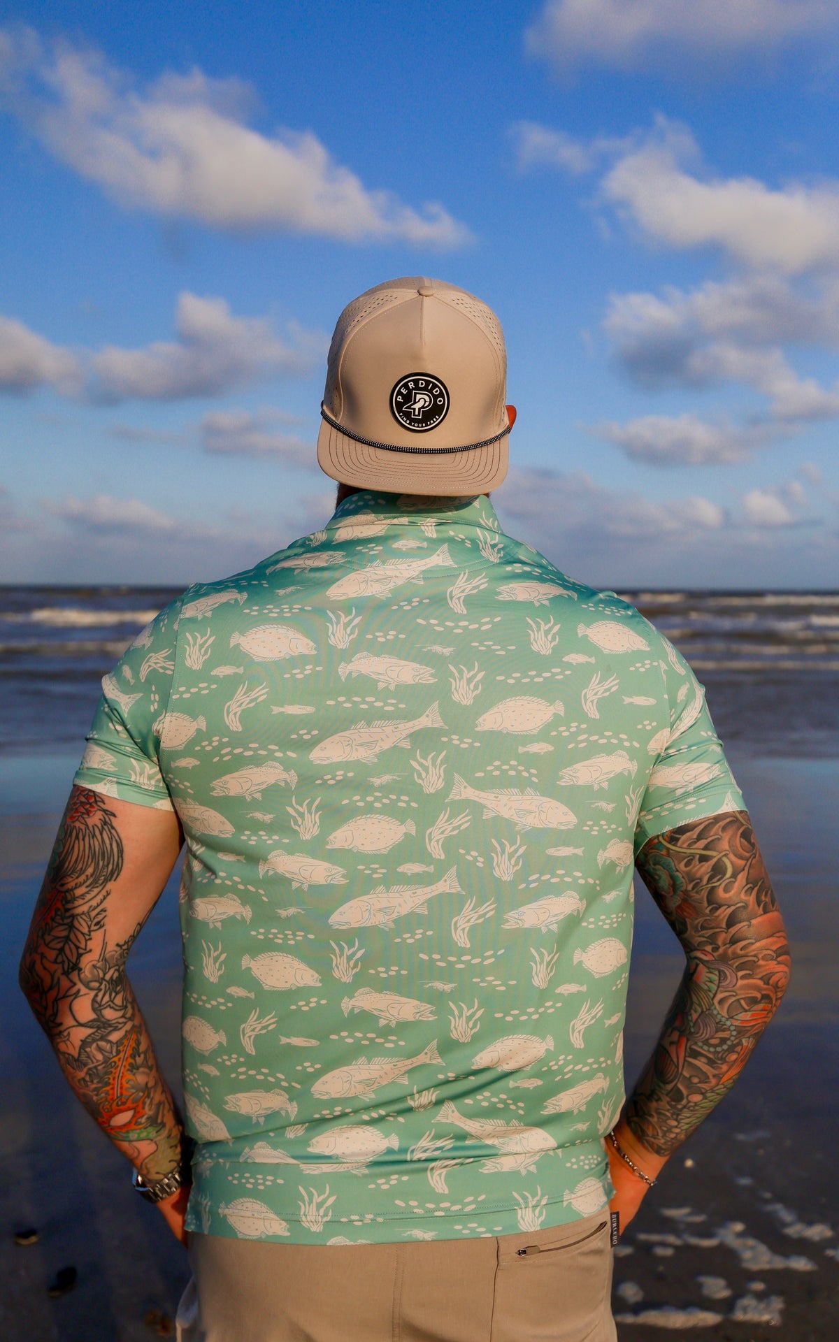 Back view of man looking out at the ocean in light green Texas Slam polo.