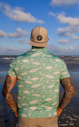 Back view of man looking out at the ocean in light green Texas Slam polo.